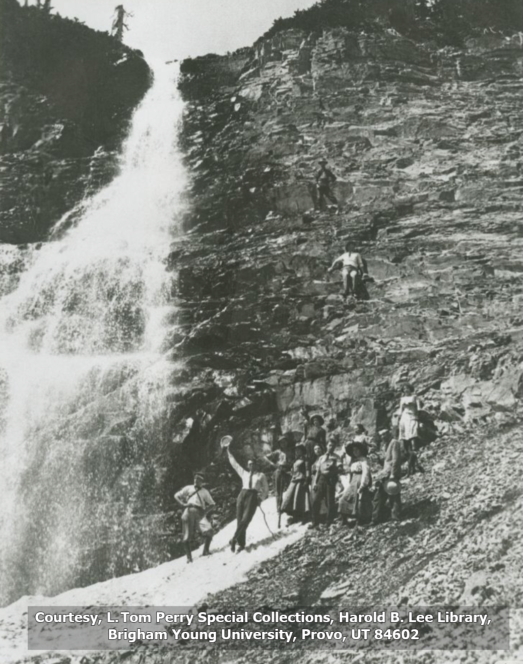 Group of students from the first summit hike stand by a waterfall in this black and white photo.