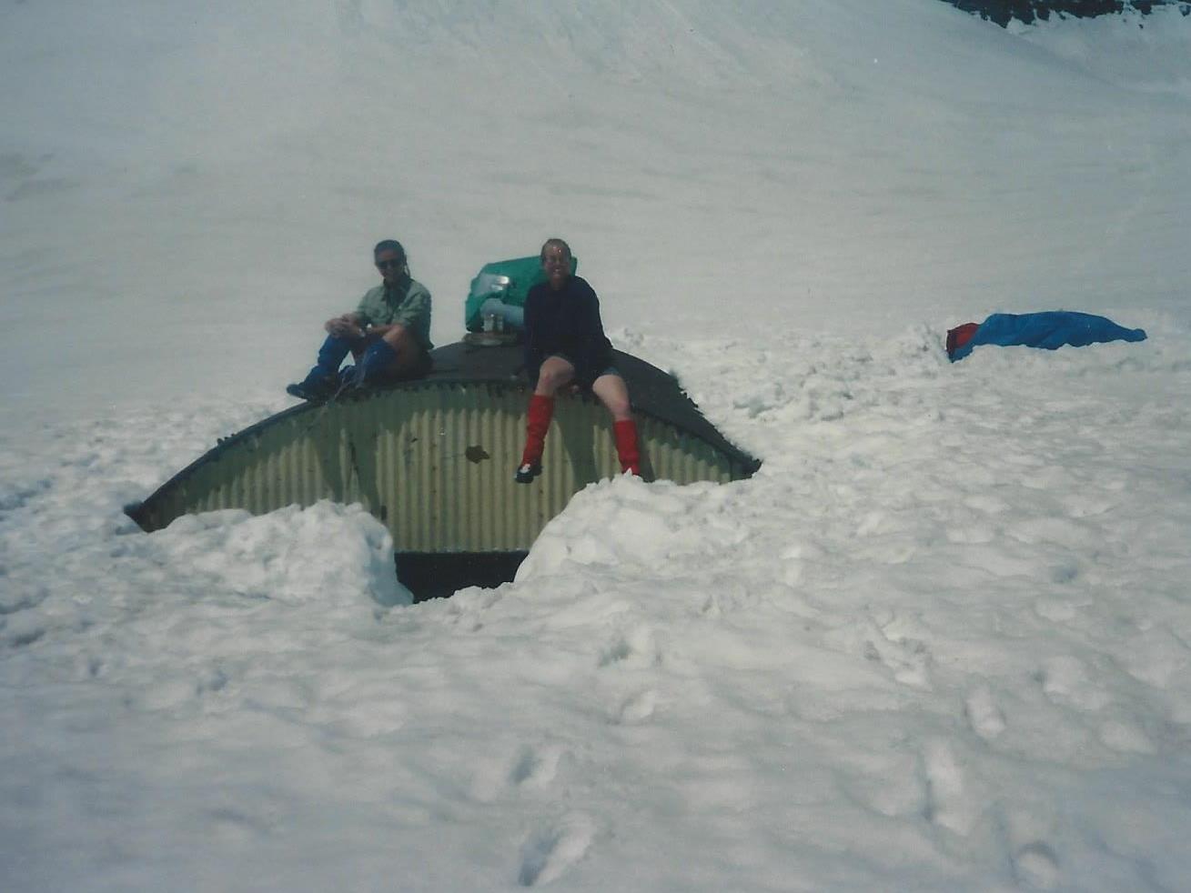 Two members of TERT sit on top of the Emerald Lake shelter, which is buried in snow